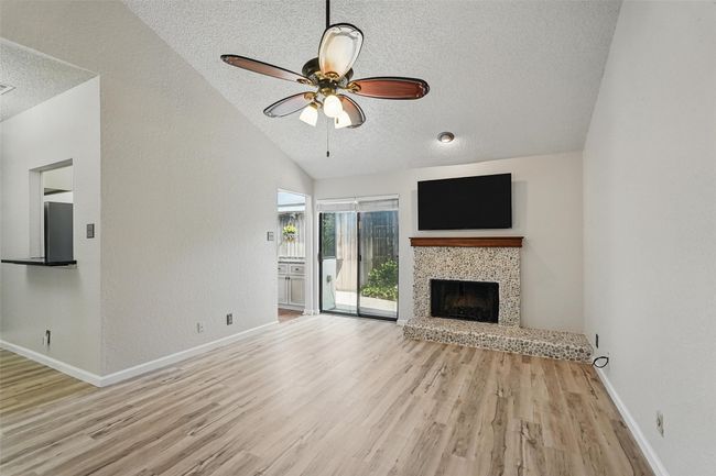 Unfurnished living room featuring a lofted ceiling, LVT, a ceiling fan, and baseboards | Image 8