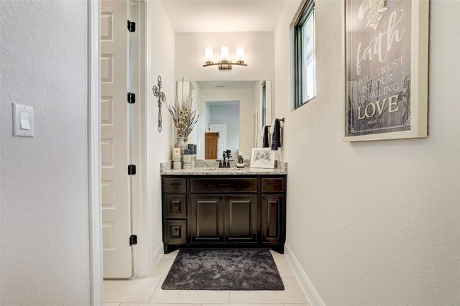Bathroom with vanity, tile patterned floors, and a textured wall | Image 22