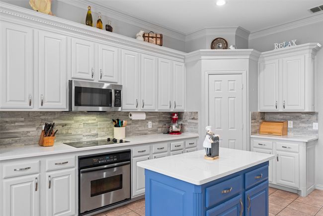 Kitchen featuring stainless steel appliances, blue cabinets, white cabinetry, and crown molding | Image 12