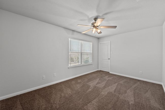 Empty room with a ceiling fan and dark colored carpet | Image 19