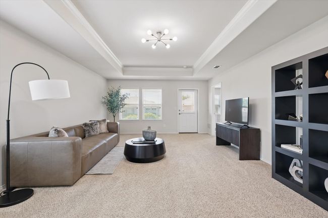 Living area with carpet floors, crown molding, a tray ceiling, and a chandelier | Image 8