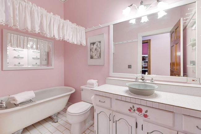 The bathroom has been outfitted with a luxurious clawfoot tub with handheld shower. Plenty of counter and storage space here as well. | Image 17