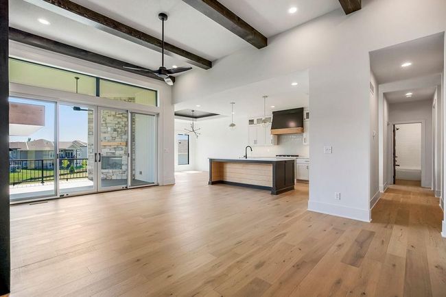Unfurnished living room with beamed ceiling, light wood-style flooring, a sink, baseboards, and recessed lighting | Image 5