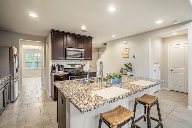 Another view of the kitchen area showing the stove and microwave. | Image 14