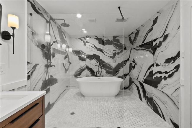 Spa-worthy wet room with dramatic black-and-white tile, freestanding tub, and dual rain shower heads. | Image 7