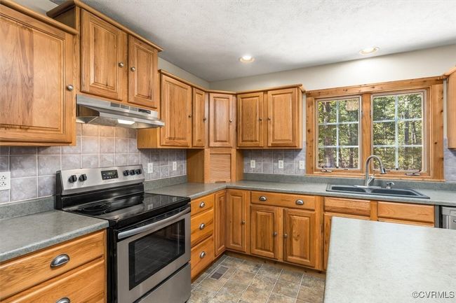 Kitchen featuring tasteful backsplash, stainless steel electric range, a textured ceiling, range hood, and sink | Image 36