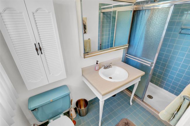 Bathroom featuring a shower with door, sink, tile patterned floors, and toilet | Image 22