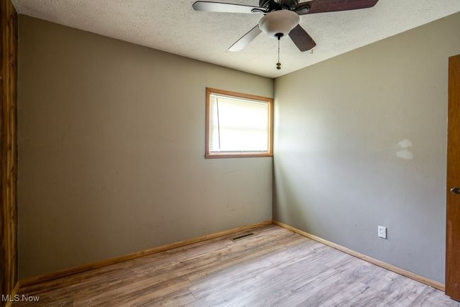 Unfurnished room featuring wood finished floors, baseboards, ceiling fan, and a textured ceiling | Image 25