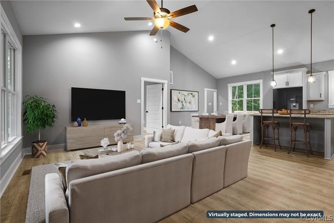 Living room with high vaulted ceiling, light wood-type flooring, and ceiling fan | Image 13