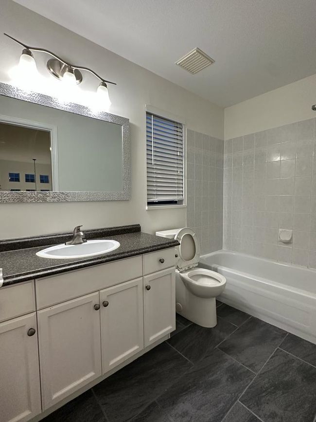 Full bath with vanity, bathing tub / shower combination, tile patterned flooring, toilet, and visible vents | Image 13