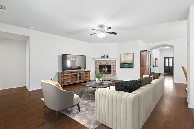 Living room featuring arched walkways, dark wood-style flooring, baseboards, a brick fireplace, and ceiling fan | Image 20