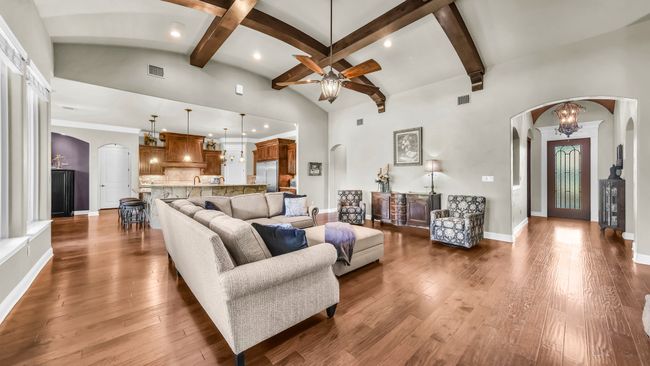 Living room featuring arched walkways, a ceiling fan, a high ceiling, wood-type flooring, and beam ceiling | Image 11