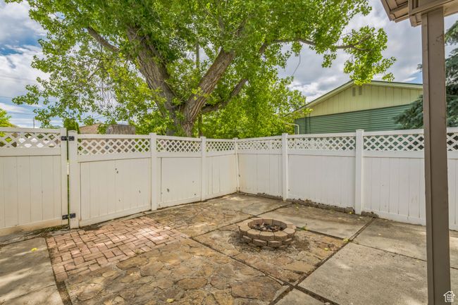 Fenced backyard with a gate, a patio area, and an outdoor fire pit | Image 5
