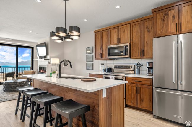 Kitchen featuring stainless steel appliances, a sink, light wood-type flooring, brown cabinetry, and recessed lighting | Image 57