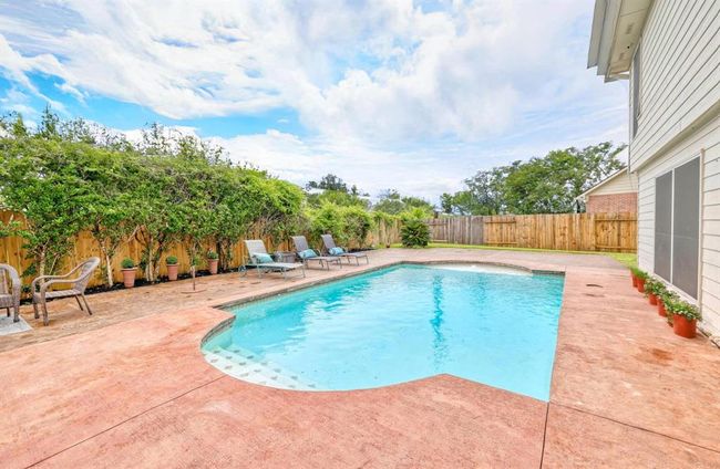 The sparkling pool is the highlight of the private backyard oasis, surrounded by lush greenery and privacy fencing. Ample deck space and multiple lounging areas make it ideal for relaxing or hosting summer gatherings. | Image 22