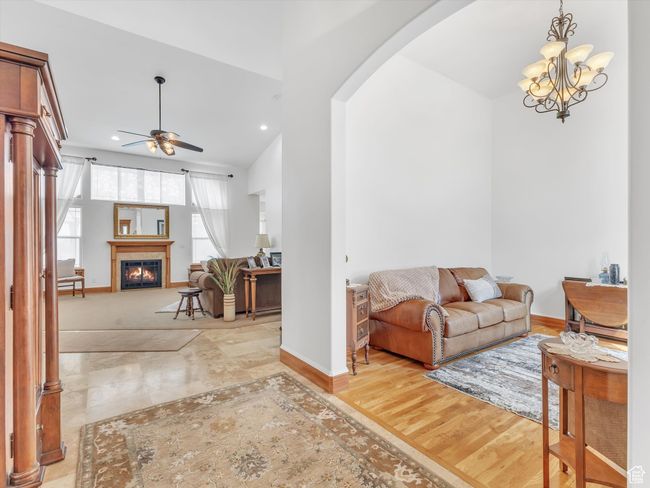Living room with arched walkways, a glass covered fireplace, baseboards, recessed lighting, and ceiling fan with notable chandelier | Image 6