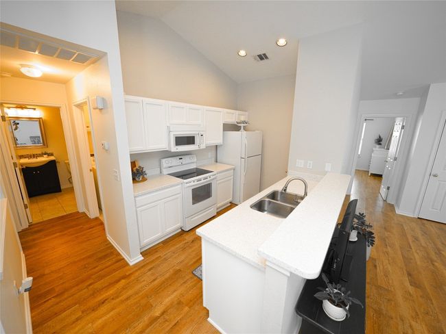 Kitchen featuring visible vents, a sink, white cabinets, and white appliances | Image 12