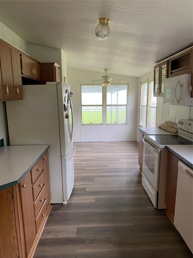 Kitchen with range, ceiling fan, fridge, dark wood finished floors, and dishwashing machine | Image 7
