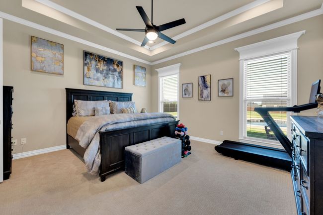 Bedroom with crown molding, a tray ceiling, light carpet, and ceiling fan | Image 17