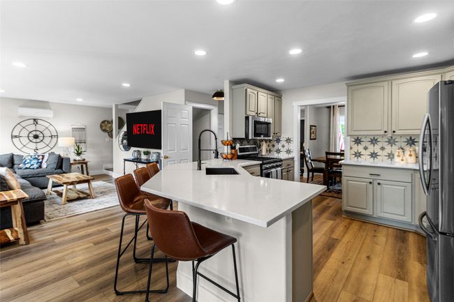 Kitchen featuring appliances with stainless steel finishes, a peninsula, open floor plan, tasteful backsplash, and a kitchen breakfast bar | Image 6