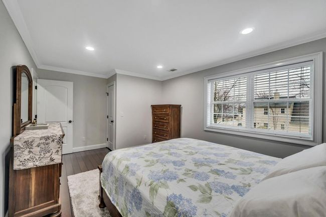 Bedroom featuring dark wood-type flooring, baseboards, visible vents, ornamental molding, and recessed lighting | Image 16
