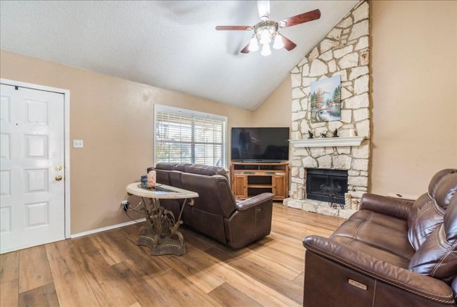 Living area with ceiling fan, a fireplace and vaulted ceiling. | Image 5