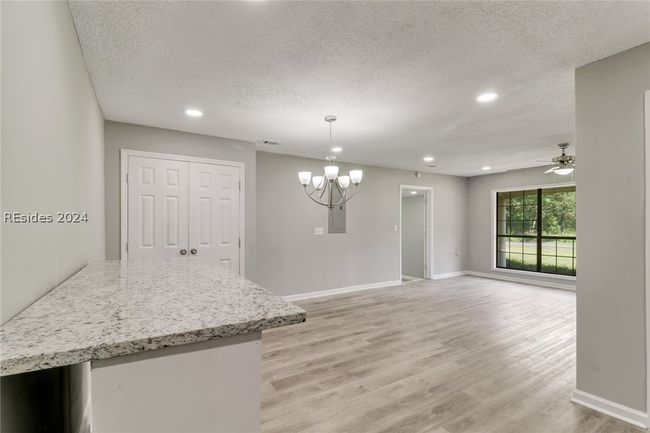 Kitchen with ceiling fan with notable chandelier, a textured ceiling, light hardwood / wood-style flooring, and pendant lighting | Image 15