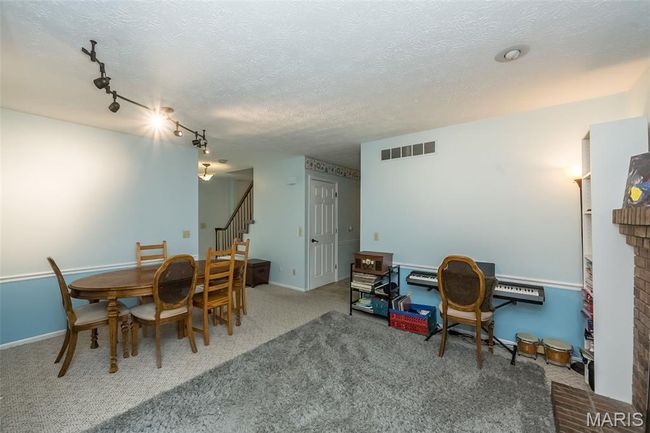 Carpeted dining space featuring stairs, rail lighting, and a textured ceiling | Image 16