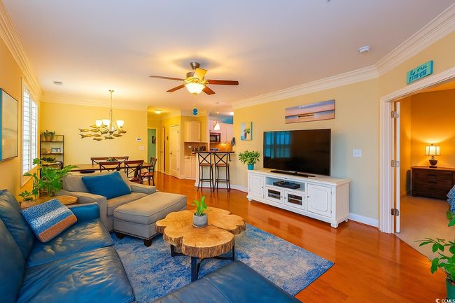 Living area with crown molding, a ceiling fan, a chandelier, and wood finished floors | Image 14