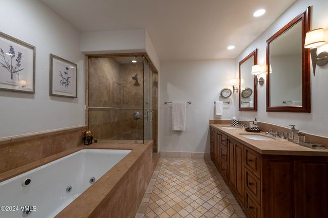 Unwind in the spa-style primary bath featuring a jetted soaking tub, large walk-in shower, and double vanities with rich wood finishes. A true sanctuary after a day on the mountain. | Image 11