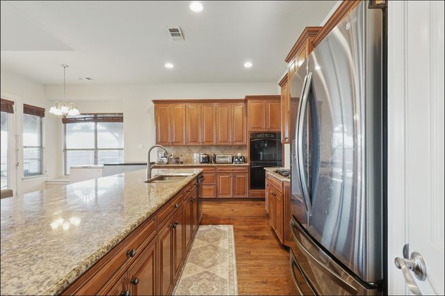 Kitchen featuring open floor plan, light stone countertops, ceiling fan, healthy amount of natural light, and recessed lighting | Image 11