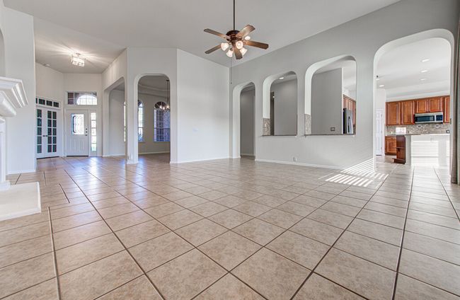 Unfurnished living room featuring light tile patterned floors, a ceiling fan, and baseboards | Image 11