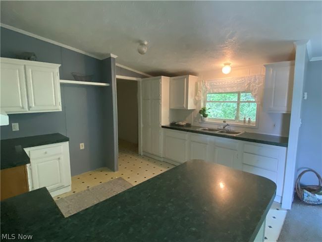 Kitchen featuring white cabinetry, sink, and light tile floors | Image 6