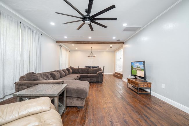 Living room with a ceiling fan, crown molding, dark wood-type flooring, recessed lighting, and a chandelier | Image 8