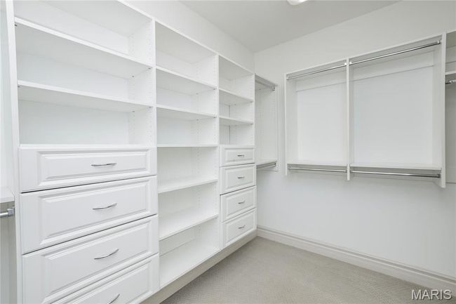 Walk-in primary closet featuring light colored carpet | Image 26