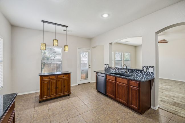 Kitchen featuring dishwasher, arched walkways, dark stone counters, pendant lighting, and recessed lighting | Image 10