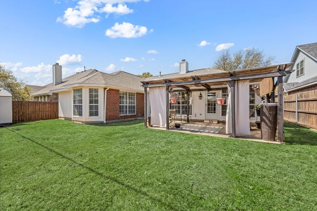 Rear view of property featuring a pergola, a chimney, a fenced backyard, and a yard | Image 39