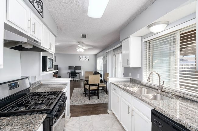 Kitchen with appliances with stainless steel finishes, sink, and white cabinets | Image 15