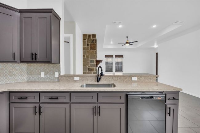 Kitchen with a tray ceiling, dishwasher, sink, and gray cabinetry | Image 15