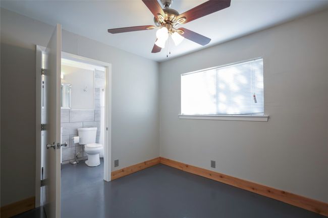 Unfurnished room featuring concrete flooring, ceiling fan, and tile walls | Image 16