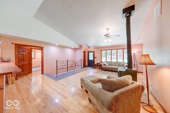 living room featuring a ceiling fan, lofted ceiling, light wood-style flooring, and a textured ceiling | Image 53