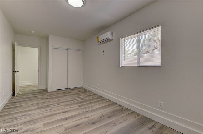 Unfurnished bedroom with a wall mounted air conditioner, baseboards, light wood finished floors, and a closet | Image 29