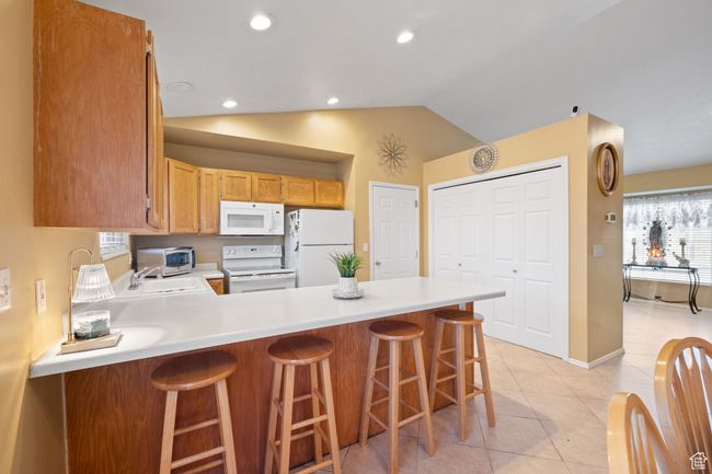 Kitchen featuring a kitchen breakfast bar, sink, white appliances, and kitchen peninsula | Image 12