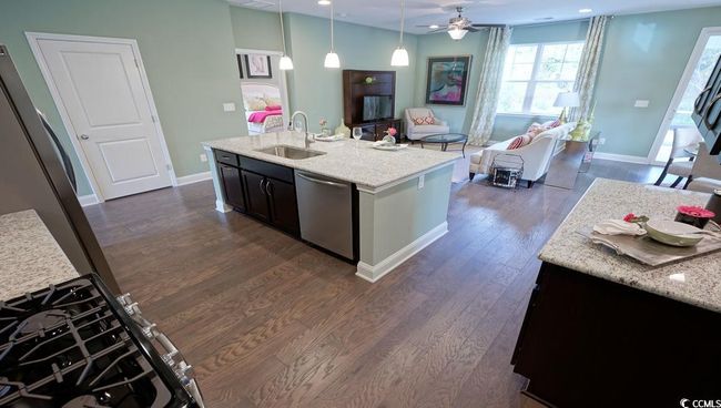 Kitchen featuring a sink, dishwasher, dark wood finished floors, open floor plan, and baseboards | Image 8