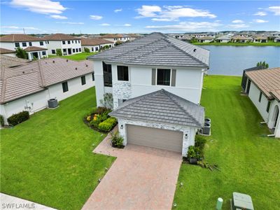 View of front of house featuring a front yard, a garage, central AC, and a water view | Image 3