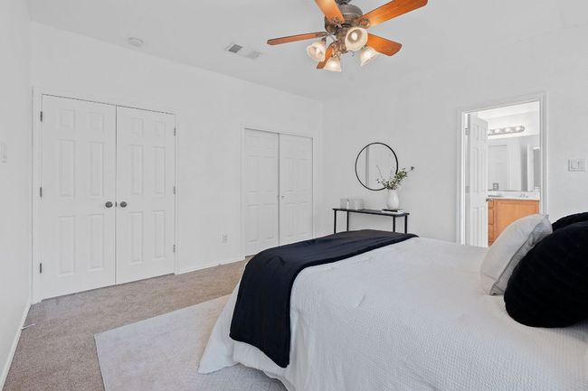 Bedroom featuring multiple closets, light carpet, connected bathroom, a ceiling fan, and baseboards | Image 17
