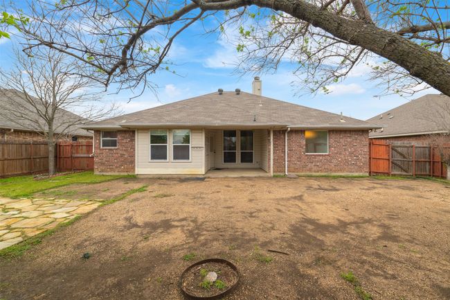 Rear view of property featuring a fenced backyard, brick siding, roof with shingles, and a patio area | Image 25