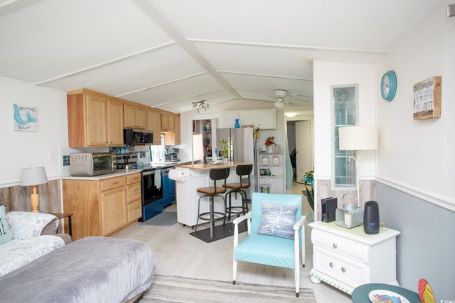 Kitchen featuring appliances with stainless steel finishes, a breakfast bar, light wood-type flooring, lofted ceiling, and a kitchen island | Image 14