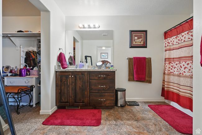 Bathroom with visible vents, baseboards, a spacious closet, vanity, and stone finish flooring | Image 25