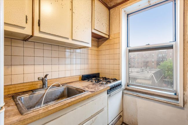 Kitchen with white gas range, light countertops, and backsplash | Image 6